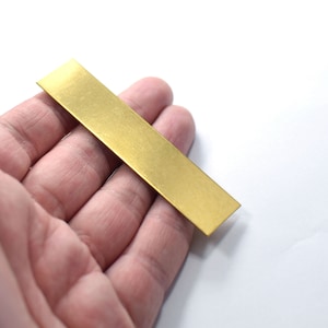 May include: A thin, rectangular piece of brass sheet metal with a brushed finish. The metal is a bright gold color.