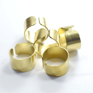 May include: Four gold-colored metal rings, each with a slightly different size and shape, are stacked on top of each other. The rings are all made of a smooth, shiny metal.