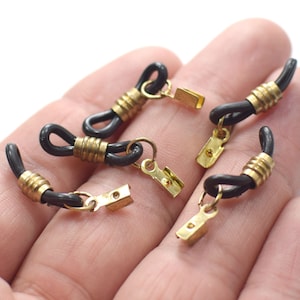 Puede incluir: Seis terminales de cadena de gafas negras y doradas. Los terminales de cadena están hechos de un material negro similar al caucho con un anillo de metal dorado y un cierre de metal dorado.