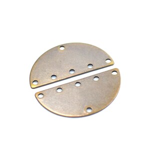 Pode incluir: Dois semicírculos de metal dourado antigo com furos ao redor das bordas. As duas peças se encaixam para formar um círculo.