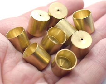 May include: A group of eight gold-colored metal caps with a small hole in the top. The caps are cylindrical and have a smooth, shiny finish.