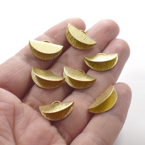 May include: Eight gold-colored metal half-circle shapes with a textured surface.
