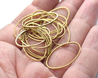 May include: A pile of gold-colored oval-shaped metal rings, likely for jewelry making, are displayed in a hand.