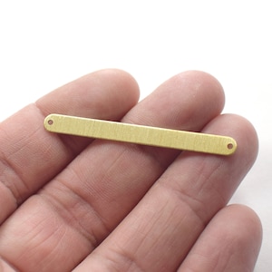 Pode incluir: Uma barra de metal de cor dourada com dois furos, perfeita para adicionar a joias ou artesanato.