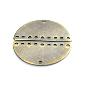 May include: Two-piece antique brass circle charm with a row of holes around the edge. The charm is split in half, with each half having a row of holes.