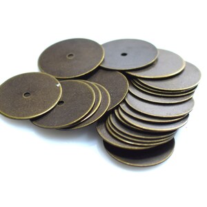 以下が含まれることがあります： 中央に小さな穴が開いた丸い真鍮色の金属製の円盤が積み重ねられています。円盤は互いに積み重ねられ、山になっています。