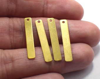 May include: Four gold-colored metal bar pendants with a hole at the top. The pendants are about 1 inch long and have a brushed finish.