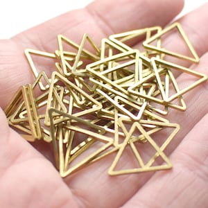 Pode incluir: Um monte de formas triangulares de metal dourado, provavelmente para fazer joias ou artesanato.