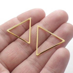 Pode incluir: Dois quadros de metal em forma de triângulo dourados. Os quadros estão abertos e parecem ser para a fabricação de joias.