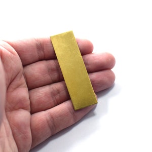 May include: A rectangular piece of brass sheet metal, approximately 2 inches by 4 inches, with a brushed finish.