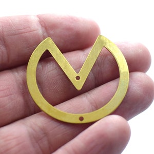 Könnte beinhalten: Ein goldfarbener Metallanhänger mit einem V-förmigen Ausschnitt in der Mitte. Der Anhänger hat eine kreisrunde Form mit einer glatten, gebürsteten Oberfläche.