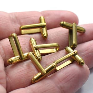 May include: A set of six gold-toned cufflinks. The cufflinks are made of metal and have a simple, classic design.