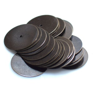 以下が含まれることがあります： 中央に小さな穴が開いた、丸いブロンズ色の金属製の円盤が積み重ねられています。