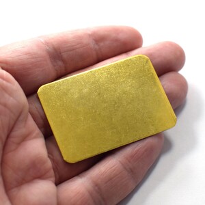 May include: A small, rectangular, gold-coloured metal sheet.