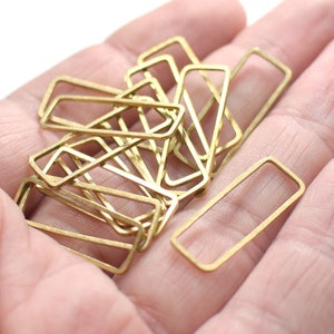 Pode incluir: Um monte de molduras retangulares de metal dourado, provavelmente para a fabricação de joias ou artesanato.