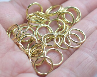 May include: A large pile of gold-colored metal jump rings. The rings are all the same size and are arranged in a random pattern.