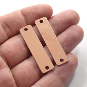 May include: Two rose gold metal rectangular tags with holes at the top and bottom. The tags are blank and ready for personalization.