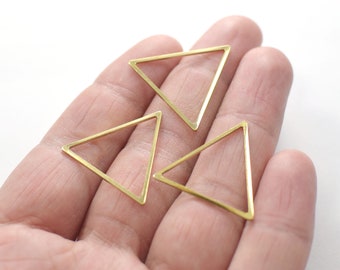 Puede incluir: Tres marcos de metal de forma triangular de color dorado. Los marcos están abiertos y parecen ser para la elaboración de joyas.