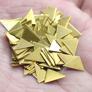 May include: A pile of gold-colored metal triangle shapes. The triangles are various sizes and are arranged in a random pattern.