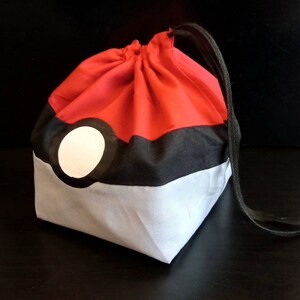 K&ouml;nnte beinhalten: Rote, schwarze und wei&szlig;e Kordeltasche mit einem Pokeball-Design.
