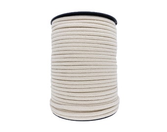 May include: A spool of natural white cotton cord, wound tightly on a black plastic spool.