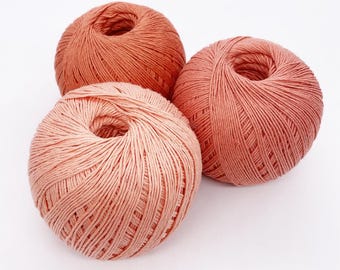 May include: Three balls of peach-colored yarn, each wound into a neat ball.