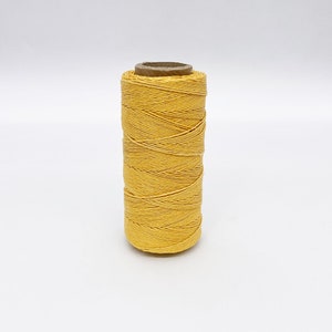 May include: A spool of yellow waxed linen thread.