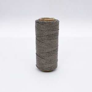 May include: A spool of gray linen thread.