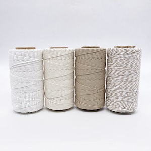 May include: Four spools of twine in white, cream, brown, and a brown and white striped pattern.