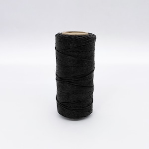 May include: A spool of black waxed linen thread.