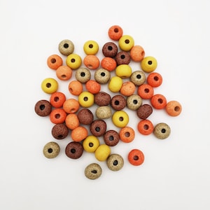 Peut inclure: Un ensemble de perles rondes en bois dans des tons de brun, orange et jaune. Les perles sont tachetées d'une texture rugueuse.