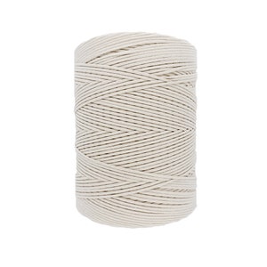 May include: A spool of natural white cotton twine. The twine is wound tightly around the spool, creating a smooth, even surface.