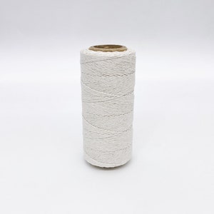 May include: A spool of white twine, wound tightly and ready for use. The twine is made of natural fibers and is perfect for crafting, wrapping, and other DIY projects.