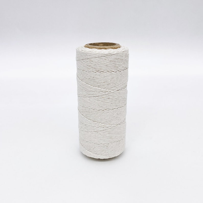May include: A spool of white twine, wound tightly and ready for use. The twine is made of natural fibers and is perfect for crafting, wrapping, and other DIY projects.