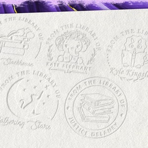 May include: Five white rubber stamps with different illustrations and text. The stamps read "From the Library of" followed by the name of the owner. The illustrations include a stack of books, an elephant, a candle, a crescent moon with stars, and a stack of books.