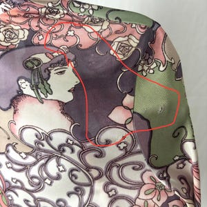 May include: A close-up of a silk garment with a floral and Art Nouveau design. The fabric features a woman's profile, roses, and swirling patterns in shades of pink, green, purple, and cream.