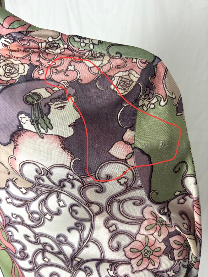 May include: A close-up of a silk garment with a floral and Art Nouveau design. The fabric features a woman's profile, roses, and swirling patterns in shades of pink, green, purple, and cream.