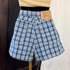 Peut inclure: Shorts en jean à carreaux bleus et blancs avec un patch en cuir Levi Strauss & Co. Les shorts ont deux poches arrière et une étiquette orange Levi's. Vêtement vintage.