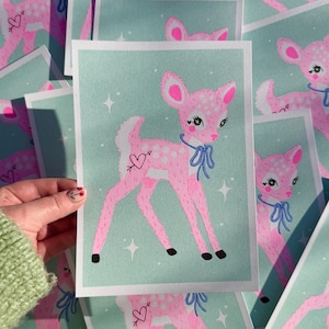 May include: A pink and white spotted fawn with a blue bow and a heart with an arrow tattoo on its hind leg. The fawn is standing on a light green background with white stars.