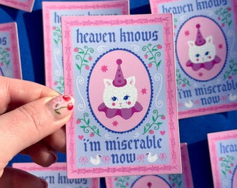 May include: A pink and blue sticker with a white cat wearing a pink and white hat. The sticker has a white border and says "heaven knows I'm miserable now" in a pink and blue font.