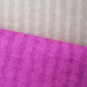 May include: Two fabric swatches, one beige with a chevron pattern and one pink with a wavy pattern.