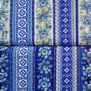 Può includere: Tessuto a righe blu e bianche con un motivo floreale. Il tessuto presenta un motivo ripetitivo di fiori e foglie blu su sfondo bianco, con motivi geometrici blu e bianchi tra i motivi floreali.