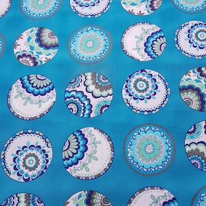 Könnte beinhalten: Türkisfarbener Stoff mit einem sich wiederholenden Muster aus weißen und blauen Kreisen mit komplizierten floralen Designs. Die Kreise haben einen silbernen Umriss.