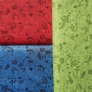 May include: Three fabric swatches with a repeating pattern of black floral designs on different colored backgrounds. The top swatch is red, the middle swatch is blue, and the bottom swatch is green.