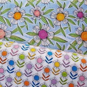 Könnte beinhalten: Zwei Stoffmuster mit Blumenmustern. Das obere Muster ist hellblau mit weißen Blumen und grünen Blättern. Das untere Muster ist weiß mit bunten Blumen und grünen Stielen.