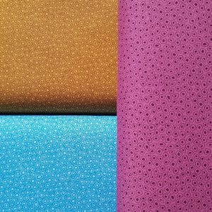 Può includere: Tre campioni di tessuto con un motivo ripetitivo di piccoli cerchi. I campioni sono di colore marrone, rosa e blu.