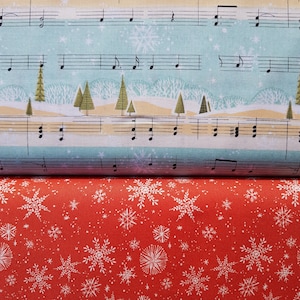 Könnte beinhalten: Roter Stoff mit einem weißen Schneeflockenmuster. Der Stoff ist über einen blauen Stoff mit einem Notenmuster und einem weißen Schneeflockenmuster gefaltet.