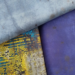 Könnte beinhalten: Drei Stoffmuster in verschiedenen Farben und Mustern. Das obere Muster ist hellblau mit einem verblassten Look. Das mittlere Muster ist ein gelbes und blaues Mosaikmuster. Das untere Muster ist ein durchgehendes Dunkelviolett.
