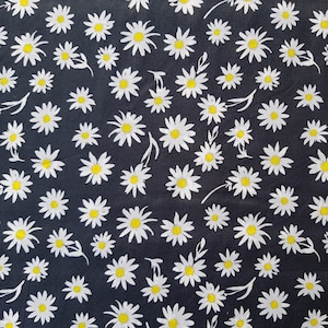Könnte beinhalten: Schwarzer Stoff mit einem weißen Gänseblümchen-Druck. Der Stoff ist mit kleinen weißen Gänseblümchen mit gelben Zentren bedeckt.