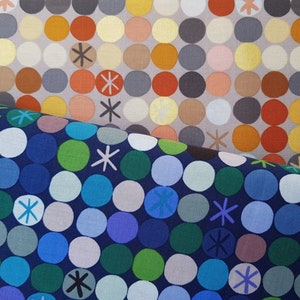 May include: Two fabric swatches with a repeating pattern of colourful circles. The top swatch is a light grey background with orange, yellow, brown, and grey circles. The bottom swatch is a dark blue background with green, blue, and grey circles. Both swatches have a white starburst pattern.